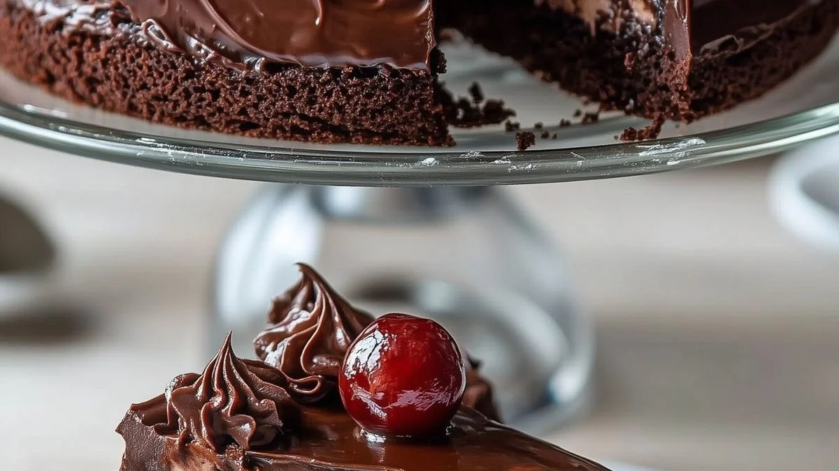 A close-up of a moist Black Forest Chocolate Cake with layers of chocolate sponge, whipped cream, and fresh cherries